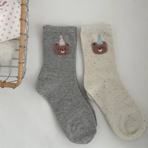 Close-up of crew socks featuring colorful rainbow yarn and cute bear embroidery detail
