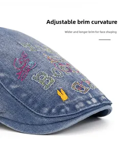 Detail of blue denim ivy cap featuring colorful letter embroidery and foldable brim feature