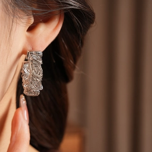 Detail of silver wire-wrapped nest design earrings worn by a model in a side view