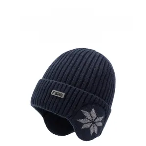 Detail of navy knit winter hat featuring ear flaps with grey snowflake patterns