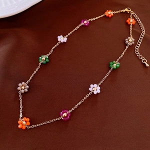 Detail view of gold chain necklace featuring colorful floral beads and adjustable clasp