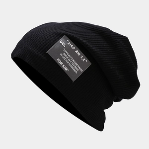 Détail d'un bonnet en maille côtelée noire avec écusson textile vintage sur fond gris