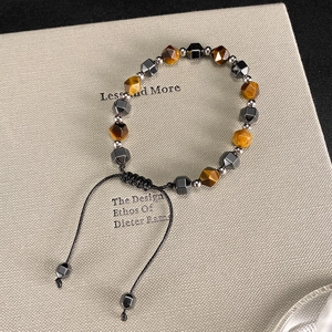 Detailed macro of tiger eye and hematite beaded bracelet with adjustable woven pull cord