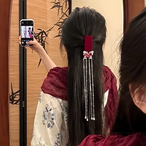 Detail of burgundy velvet butterfly hair clip with pearl tassels on long black hair