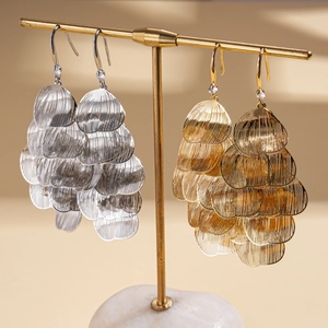 Elegant gold and silver metallic layered petal tassel earrings on marble stand