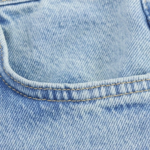 Macro view of high-quality light blue denim fabric with classic yellow stitching detail
