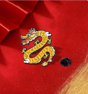 Detail of yellow dragon enamel pin with black rubber backing on festive red background
