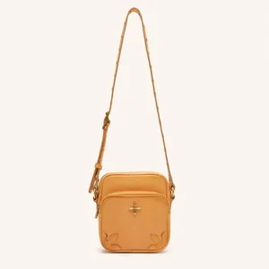 Detail der vintage gelben Leder-Gürteltasche mit goldenem Kreuz und geprägter Naht