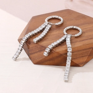 Close-up of silver titanium steel earrings with long rhinestone fringe and square zircons