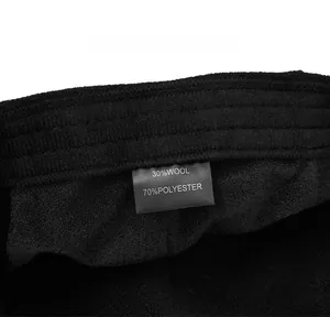 Detail of fabric care label showing 30% wool and 70% polyester blend on a black cap