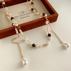 Vintage style necklace featuring pearls and tiger eye stones on a velvet jewelry tray