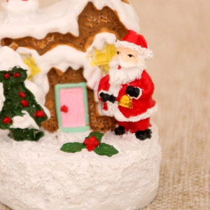 Macro shot of miniature Christmas resin Santa Claus and snow house scene decor