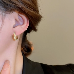 Detailed close-up of a vintage-style gold hoop earring with zircons and pearls on model