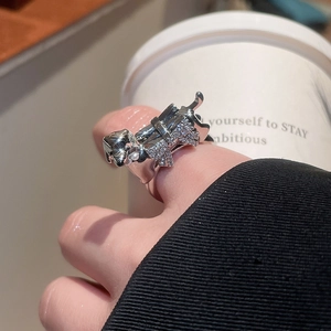 Macro detail of silver puppy ring with pavé zircon stones on white coffee cup background