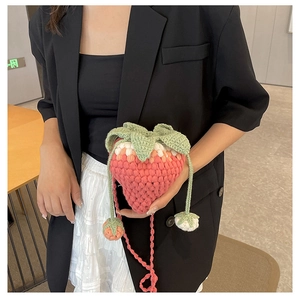 Detail of pink knitted strawberry bucket bag with handmade crochet texture and leaf accents