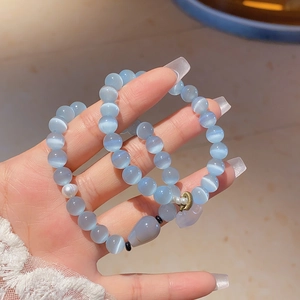 Detail of light blue cat eye stone beaded bracelets with pearl and agate pendant charms