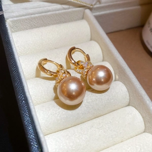 Gros plan détaillé des boucles d'oreilles perles dorées avec pierres de zircone brillantes