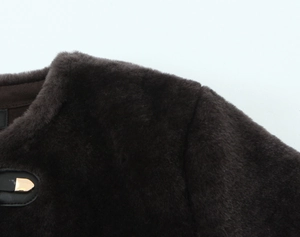 Detail of dark brown faux fur jacket featuring a gold metal buckle with black leather base