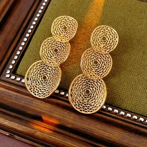 Detailansicht goldener hohler Rundohrringe auf Vintage-Hintergrund mit Metallstruktur