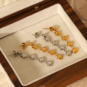 Détail de boucles d'oreilles pendantes cœur en or et argent dans une boîte à bijoux