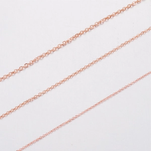 Detailed view of three rose gold stainless steel cross chains in various thicknesses