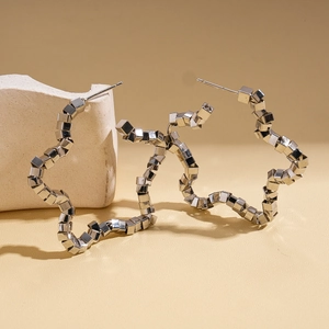 Detailed view of silver geometric star earrings on a minimalist stone display stand