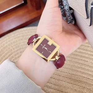 Elegant gold square watch with burgundy leather strap and dial worn by a model