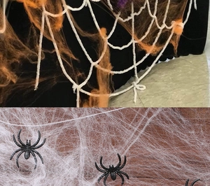 Stretchable white and orange spider web decorations with black plastic spiders for Halloween
