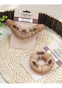 Detail view of boomerang and ring pet chew toys with cleaning textures on a straw mat