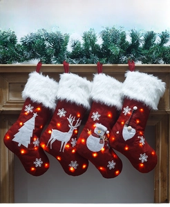 Detail showing four LED lighted red Christmas stockings hanging on a wooden fireplace mantle