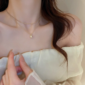 Detail of elegant gold double-layered necklace with pearl and bead chain on a model