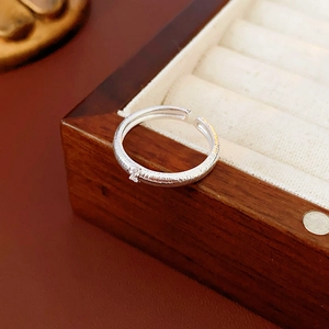 Dettaglio macro di anello regolabile argento con finitura spazzolata e zircone
