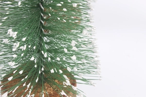 Macro shot of realistic green pine needles with white snow flocking on a wooden base