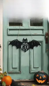 Detail of black bat-shaped Boo sign hanging on a vintage door for Halloween decor