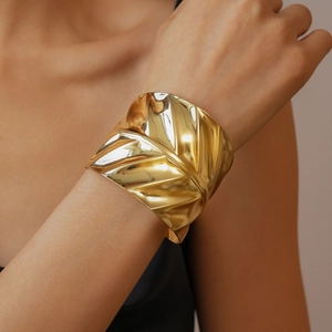 Macro shot of gold geometric leaf texture on bold metal cuff bracelet for women