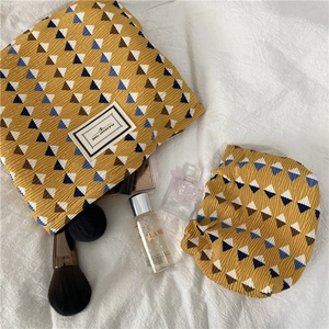 Close-up of pleated ginger storage bag set with geometric triangles and tag