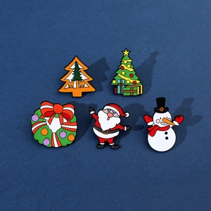 Close-up of five colorful enamel Christmas brooches featuring Santa, snowmen, and trees
