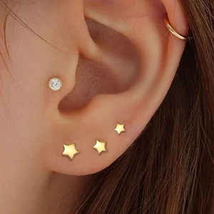 Close-up of gold star and diamond earrings set worn on earlobe and cartilage
