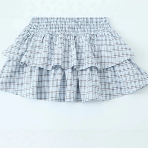 Light blue plaid mini skirt featuring tiered ruffle layers and elastic smocked waist