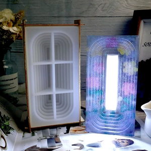 Macro shot of tiered oval silicone mold and finished resin lamp with glowing dried flowers