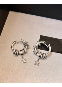 Close-up of silver star earrings with micro-set zircons and tassel details