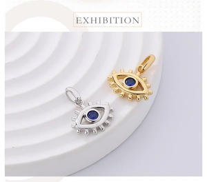 Close-up of gold and silver evil eye pendants with blue zircon on textured round stands