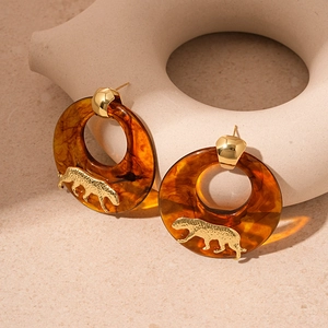 Retro amber resin hoop earrings with gold tiger metal accents on artistic stone stand