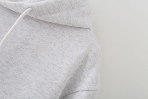 Detail of light gray knitted hoodie showing shoulder seam and adjustable drawstring