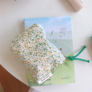 Close-up of floral cotton pouch with green woven zipper pull and simple wish label