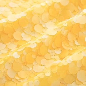 Detailed close-up of shiny yellow sequins densely stitched on a stylish fashion skirt