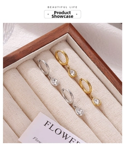 Detailed display of silver and gold teardrop zircon hoop earrings in luxury jewelry box
