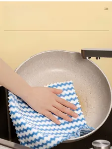 Macro view of blue wave-patterned microfiber cloth cleaning a non-stick frying pan