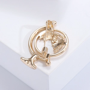 Macro shot of a golden globe brooch on white pedestal showing fine metallic details