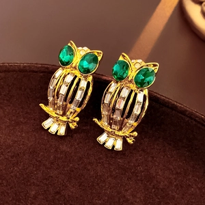 Detailed macro shot of vintage owl stud earrings with green eyes and clear crystals